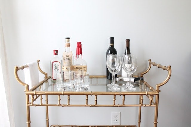 A close up of a Brass Bar with various glasses and liquor on it.