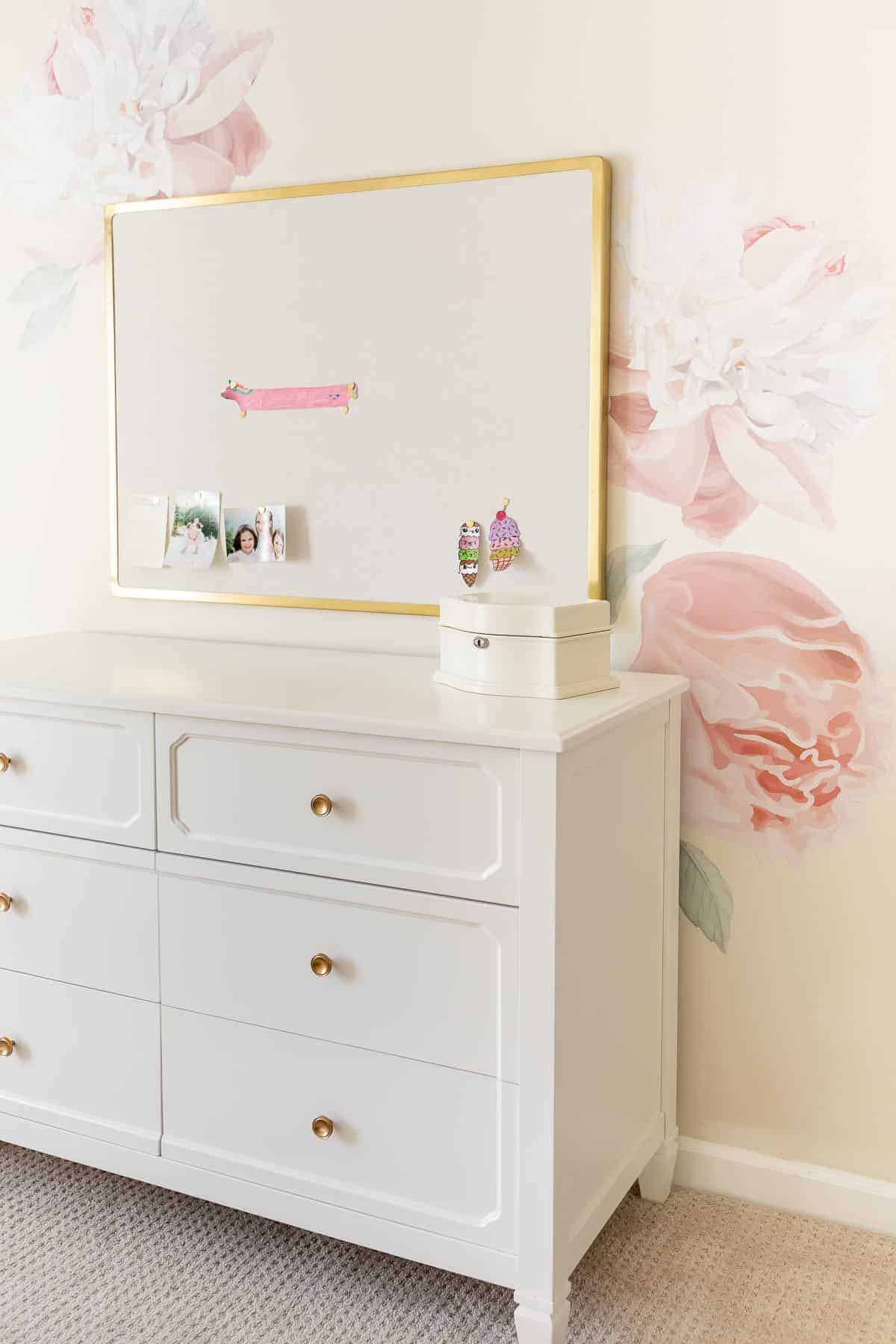 A floral decal on the wall of a pink and gold girly bedroom.