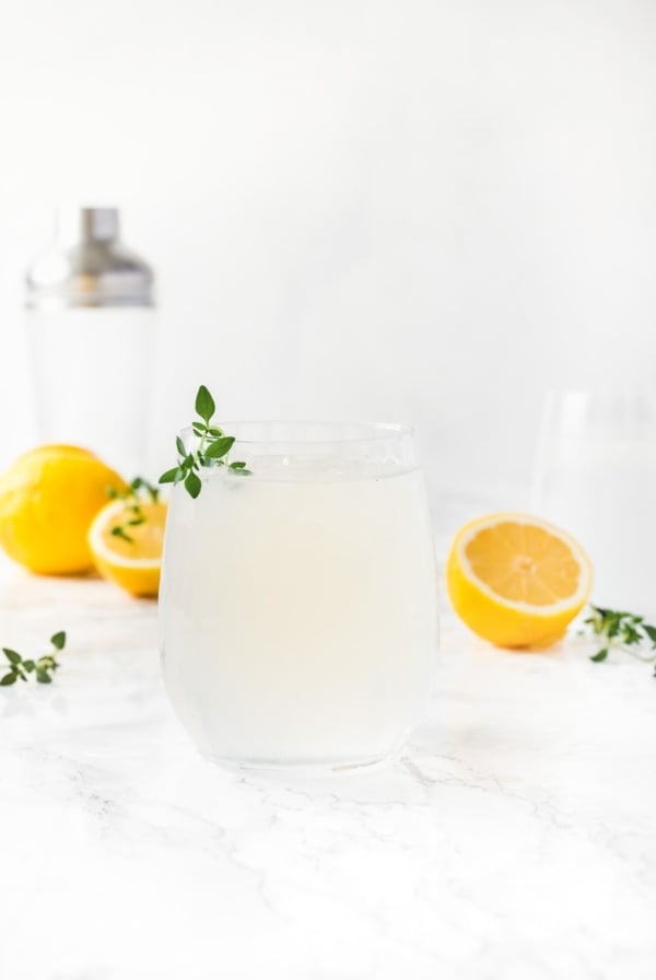 A vodka lemonade cocktail with sliced lemons in the background
