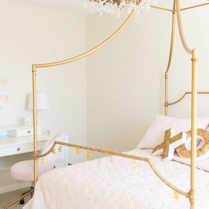 A tween girl bedroom with a gold bed and a white desk, blush pink bedding