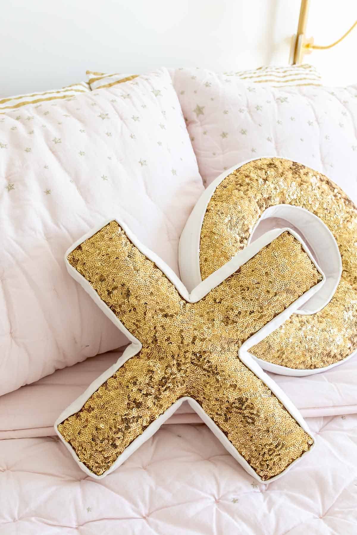 Sequined XO pillows on blush pink bedding.