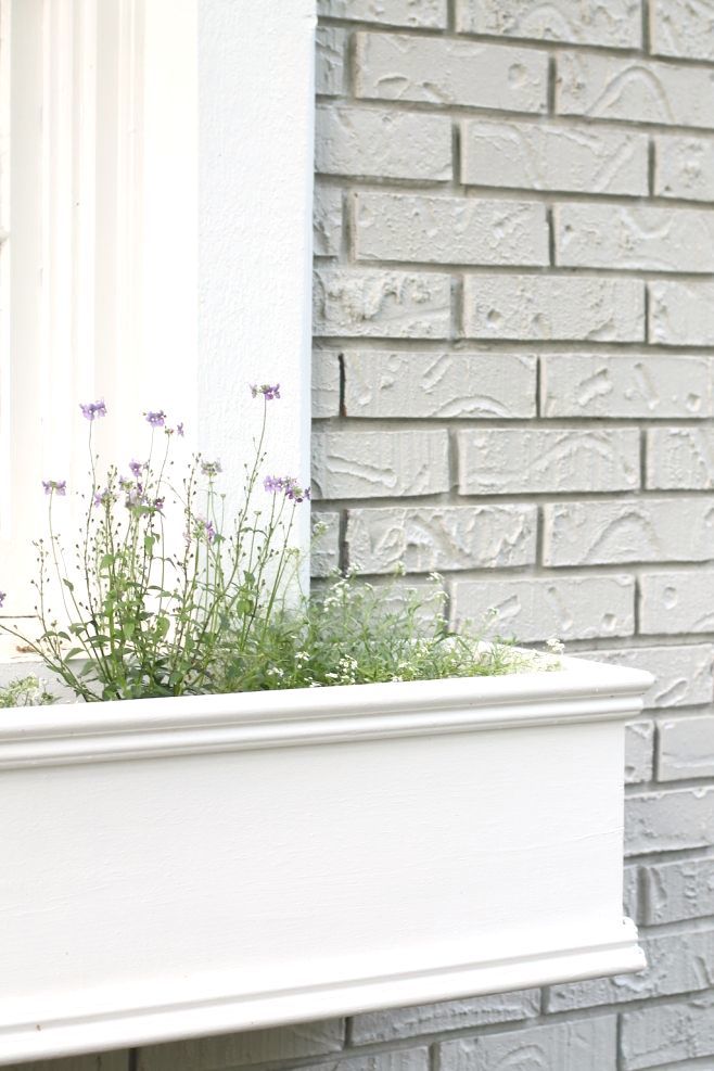 Simple white window box on grey brick house