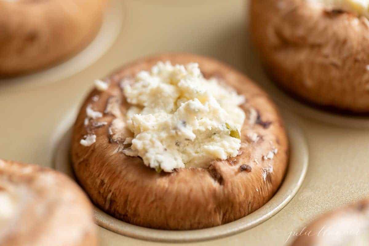 Fresh mushrooms in a gold muffin pan to make a stuffed mushroom recipe.