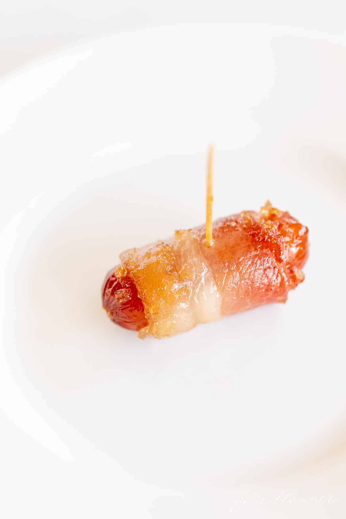 bacon wrapped lil smokie on white plate