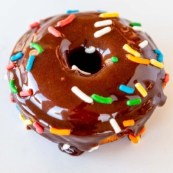 A homemade baked donut covered in chocolate frosting and sprinkles.