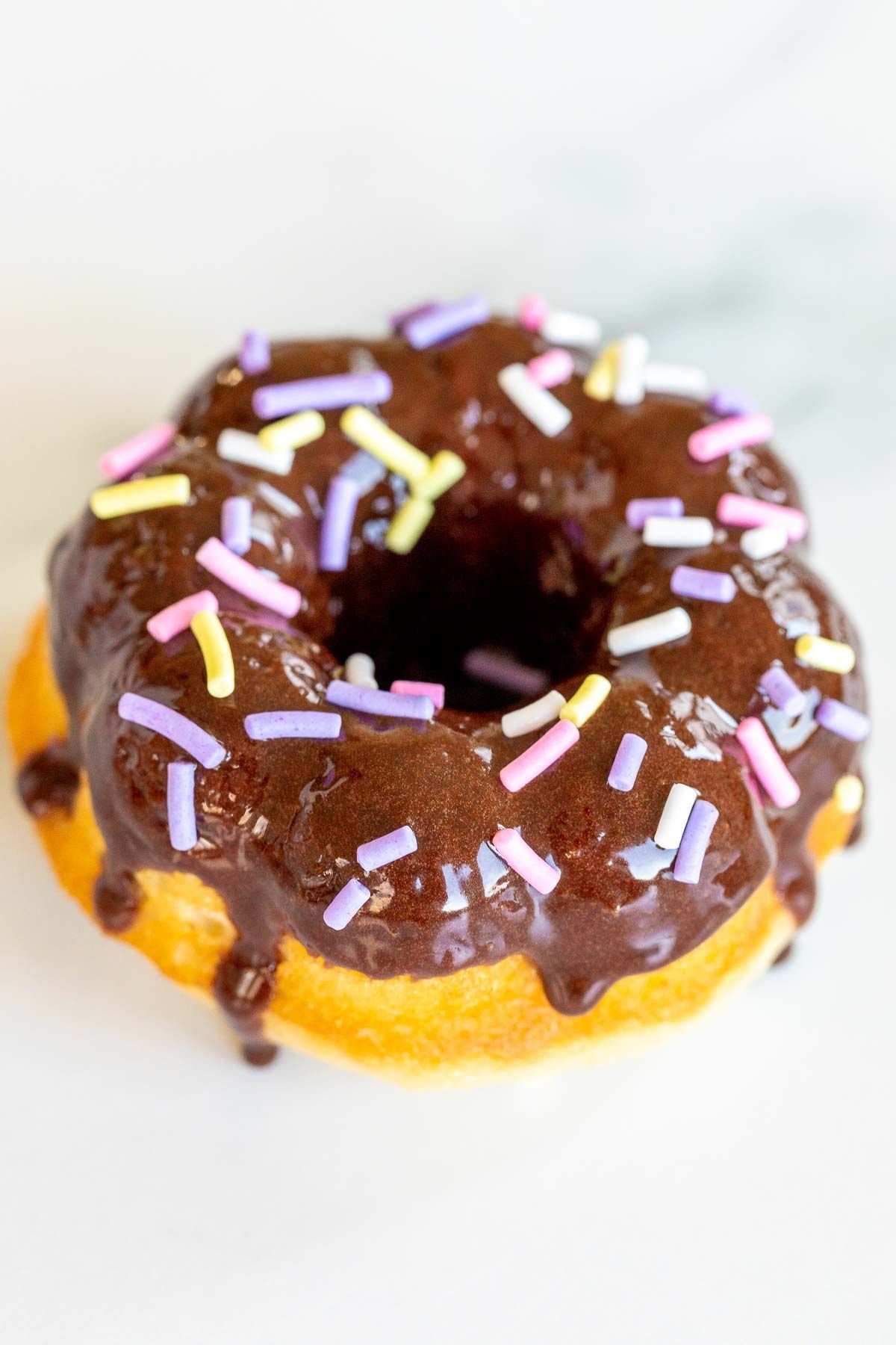 A homemade baked donut covered in chocolate frosting and sprinkles.