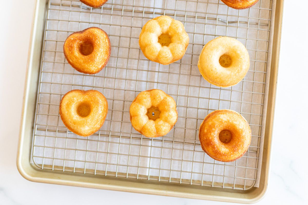 Baked cinnamon sugar donuts on a gold baking sheet and wire rack.