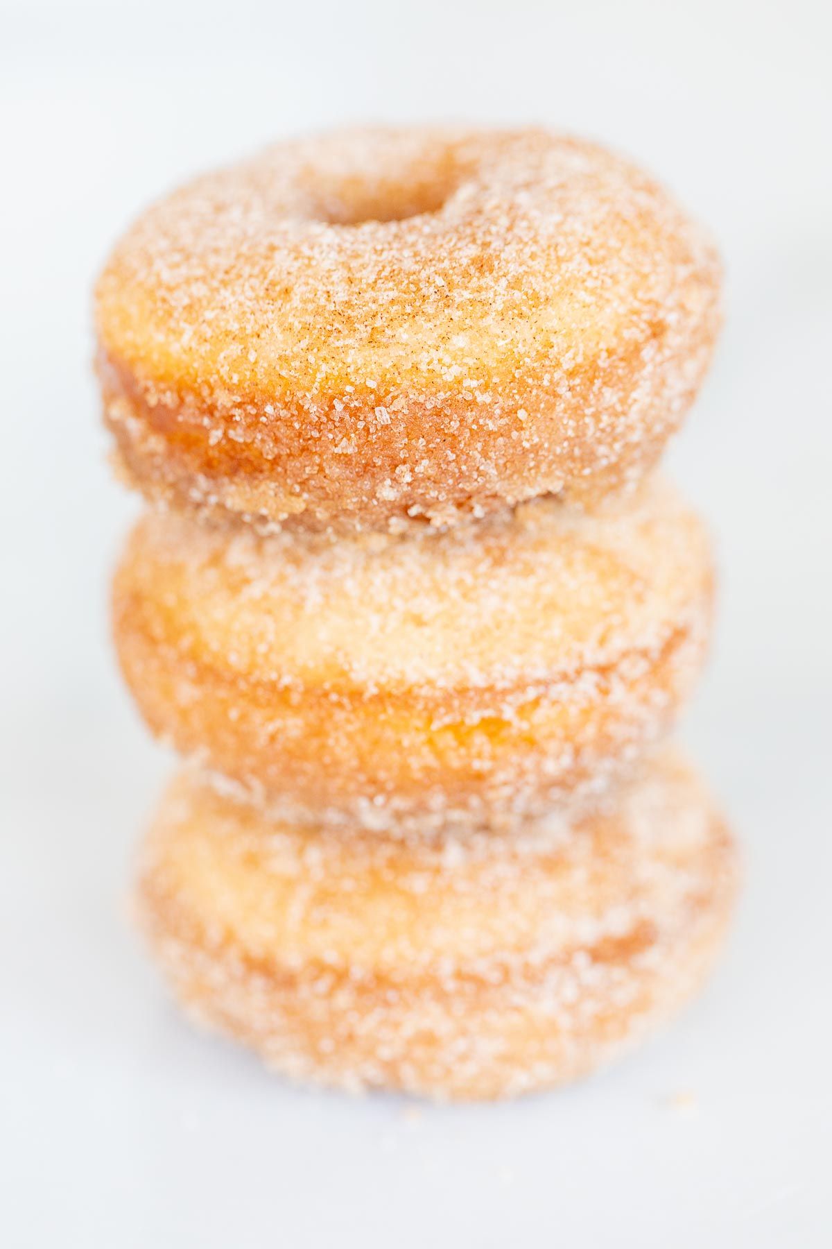 Cinnamon sugar donuts stacked on a marble countertop.
