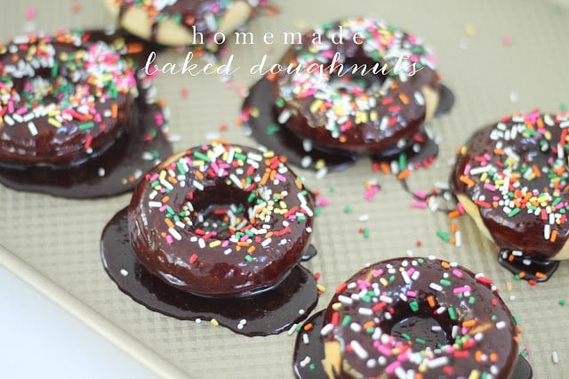 homemade baked doughnuts with chocolate icing on a baking sheet