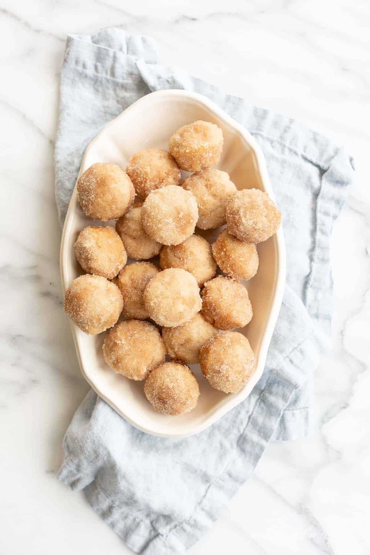 cinnamon muffins in a cream dish on blue napkin and marble counter