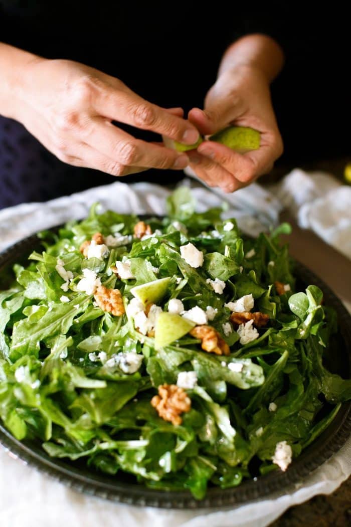 pears being tossed into pear salad on a silver platter