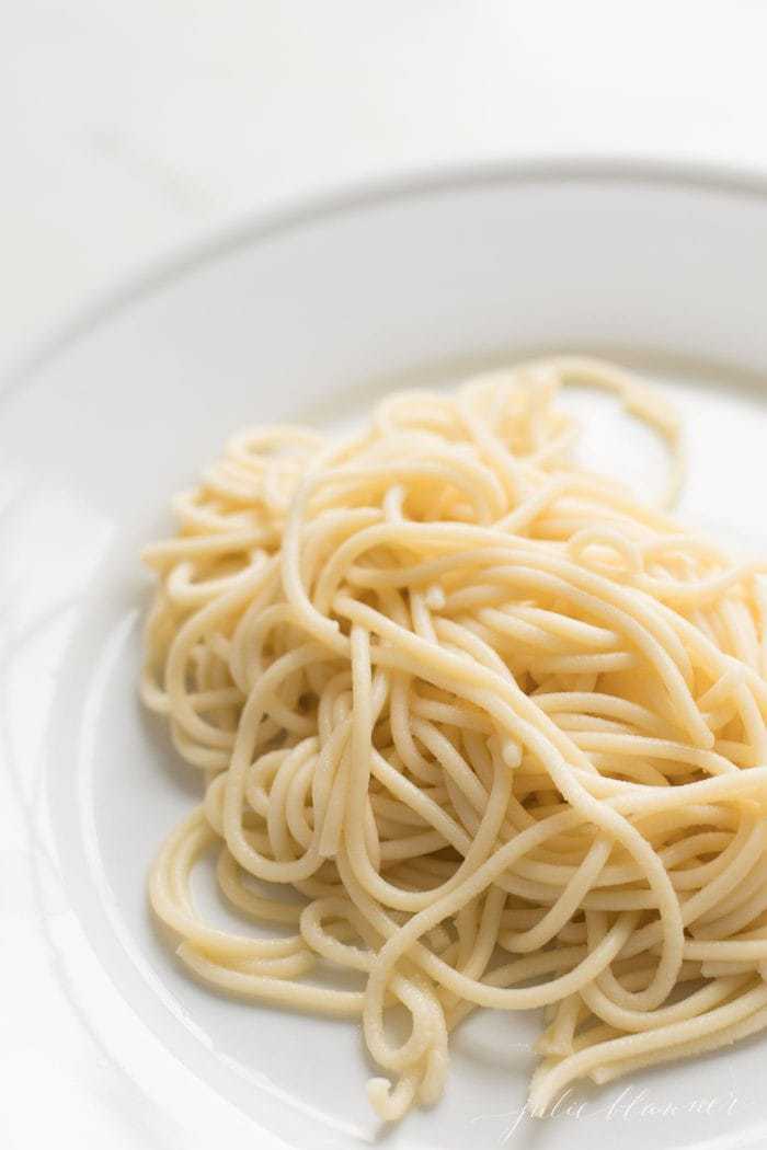 a white plate filled with a swirl of homemade egg noodles.