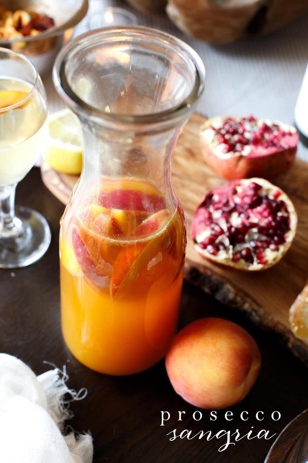 Prosecco sangria with peaches and pomegranates surrounding 