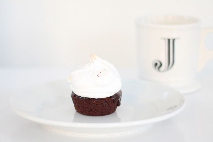 A chocolate brownie hot chocolate cake, single serving on a white plate topped with meringue.