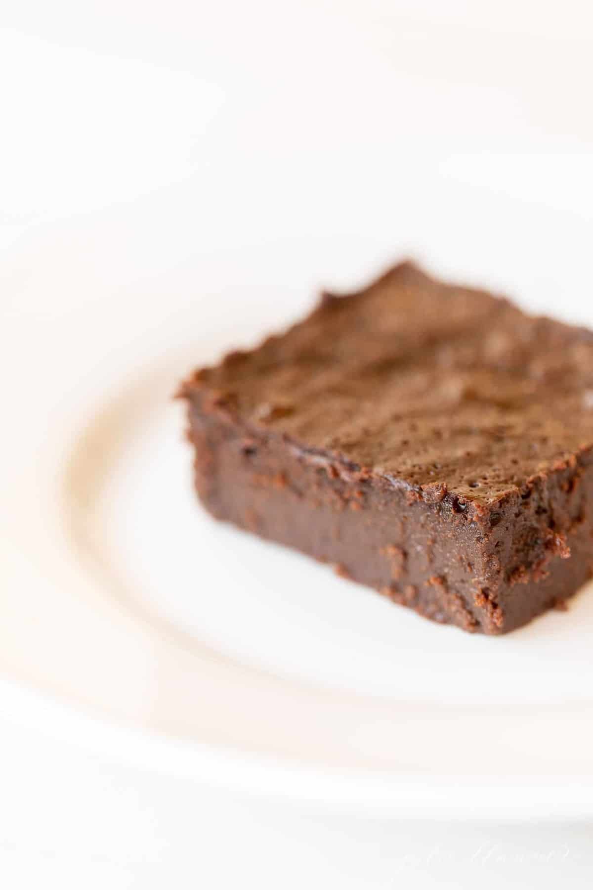 White plate with a slice of flourless brownies. 