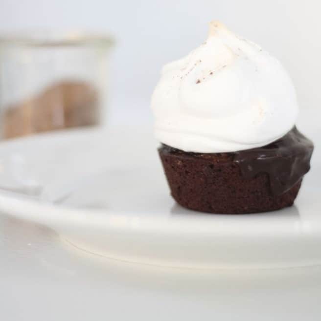A single serving of a hot chocolate cake topped with meringue on a white plate.