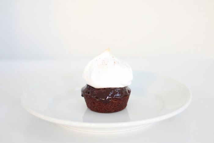 A single serving of a hot chocolate cake topped with meringue on a white plate.