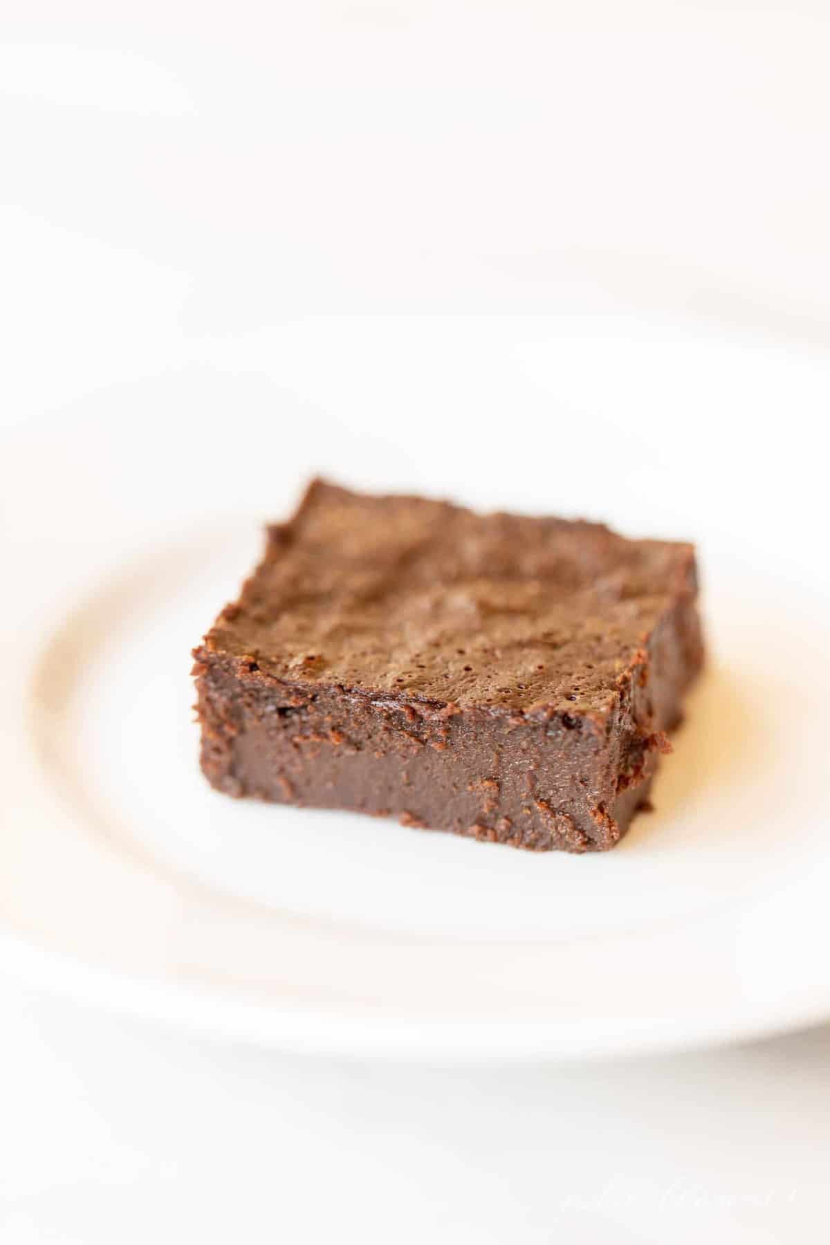 White plate with a single decadent gluten free brownie slice. 