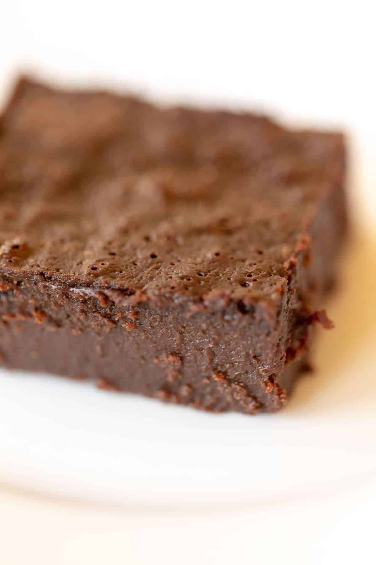 White surface with a single decadent gluten free brownie slice. 