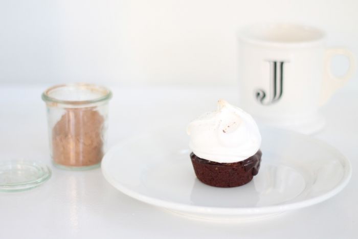A single serving of a hot chocolate cake topped with meringue on a white plate.