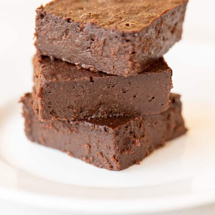 White plate with a stack of three no flour brownies.