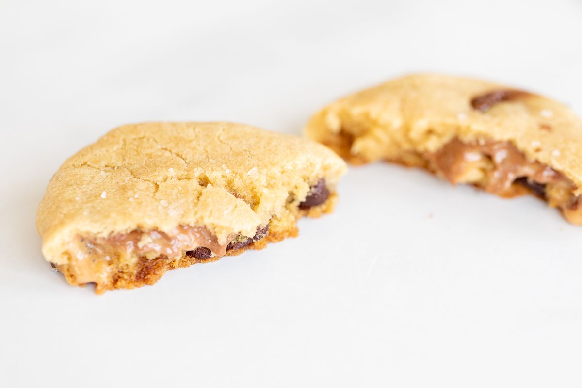 A salted caramel chocolate chip cookie, broken into two pieces.