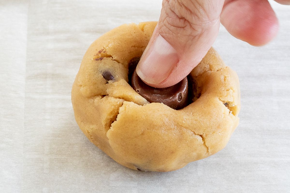 A rolo candy resting on top of a ball of cookie dough.