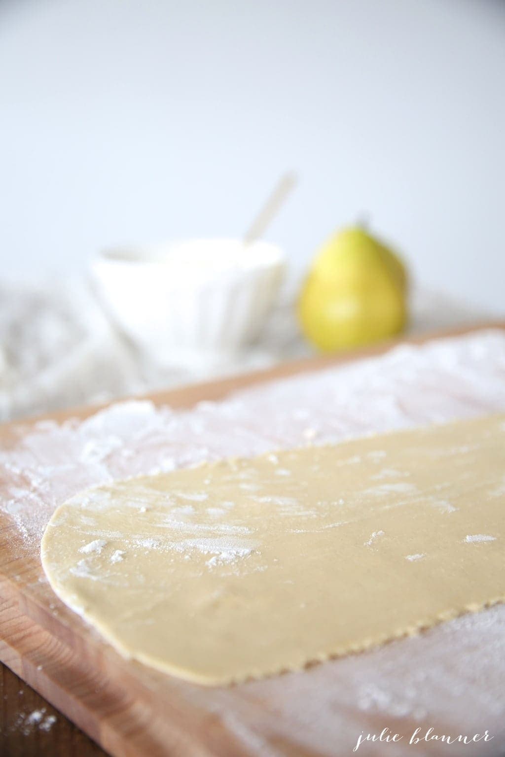 A thin sheet of pasta on a floured wooden surface. 
