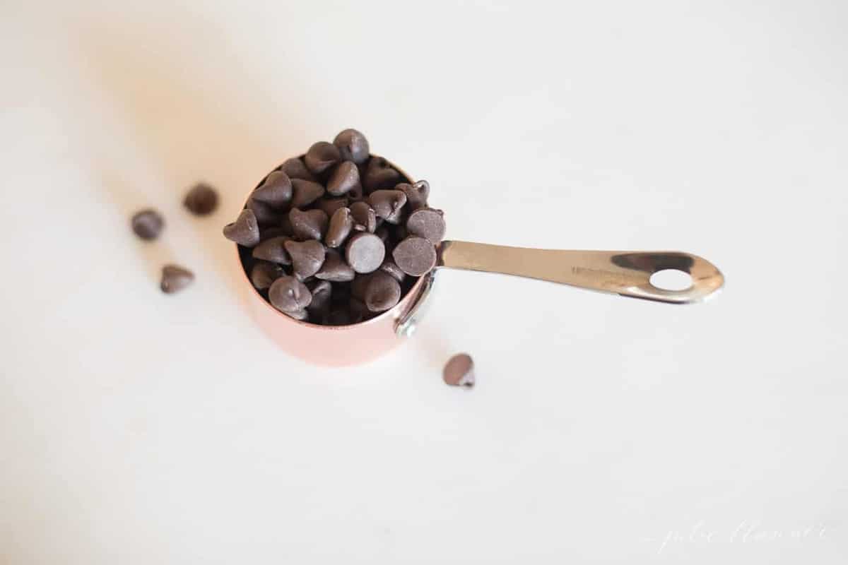 chocolate chips overflowing out of a measuring cup