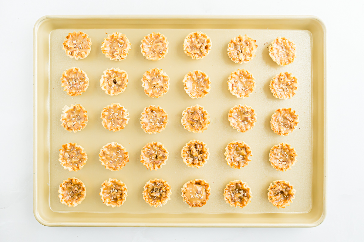 A baking sheet with a tray of mini pecan pie bites on it.