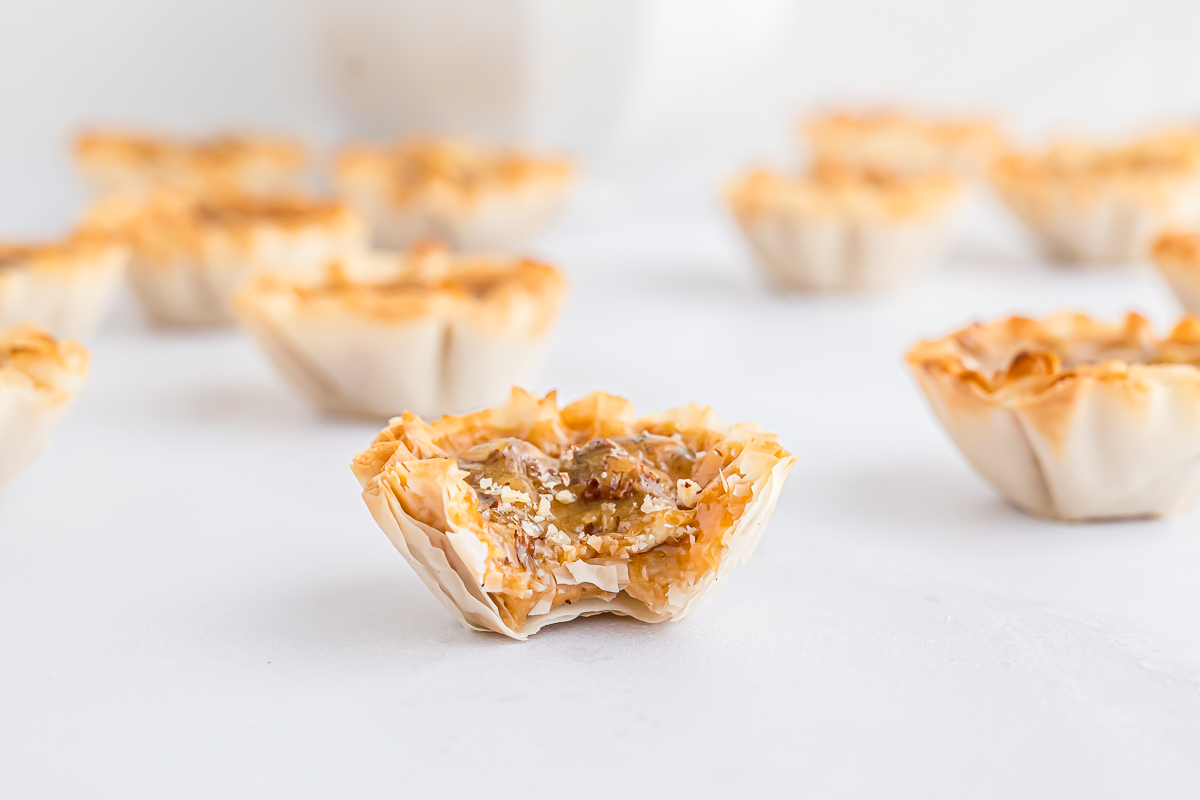 A group of Mini Pecan Pie bites on a white surface.