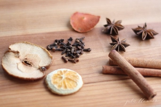 dry apple and orange slices with whole cloves, cinnamon, star anise on wooden coutertop