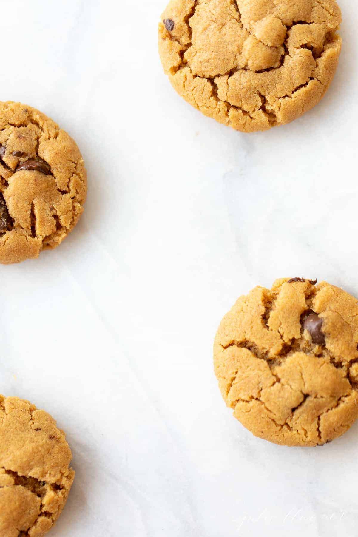 four gluten free cookies with peanut butter and chocolate chips on marble counter