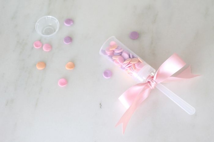 colorful sprinkles scattered and plastic confetti popper with a ribbon