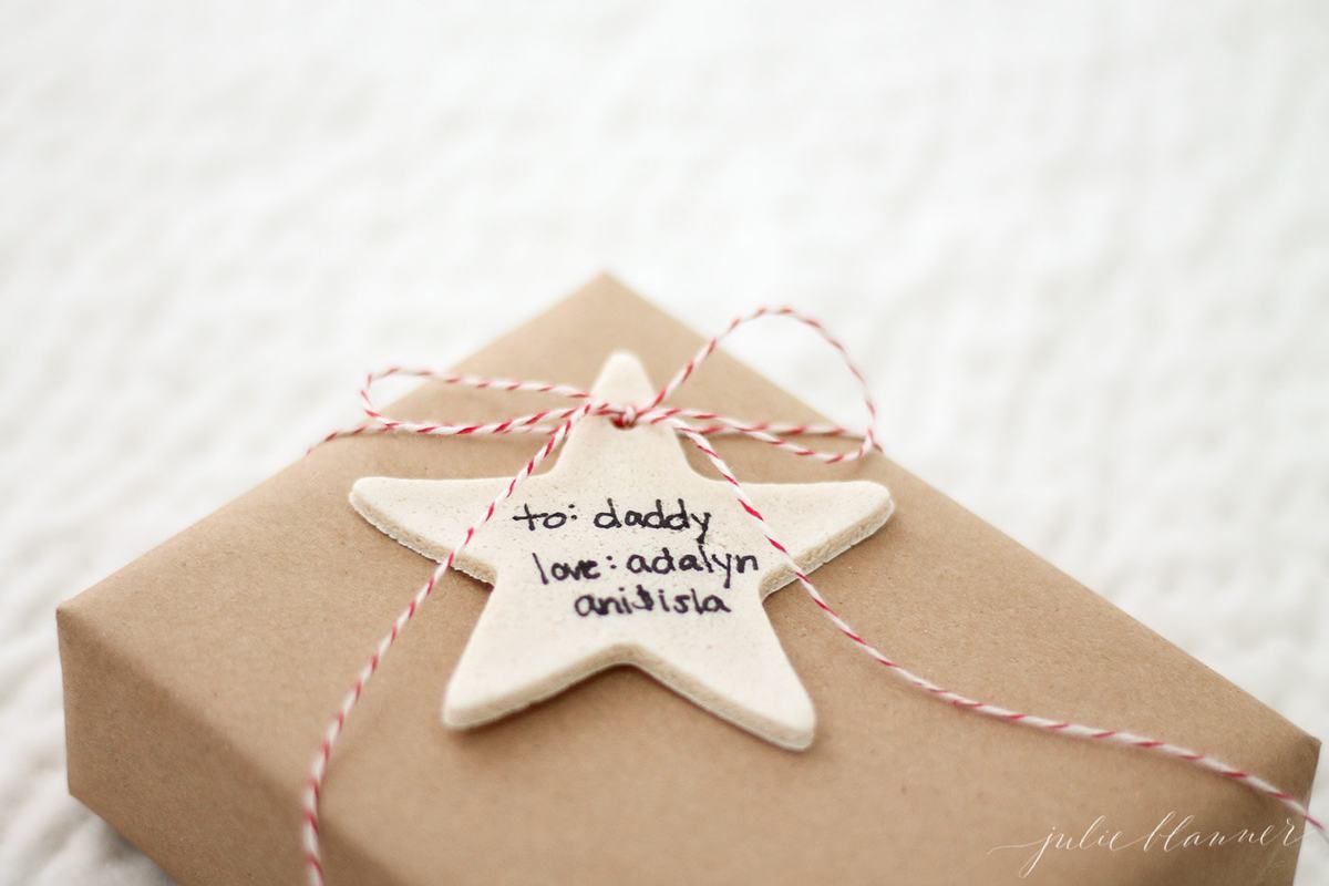 salt dough ornament gift tag in the shape of a star, tied on gift wrapped in brown paper.