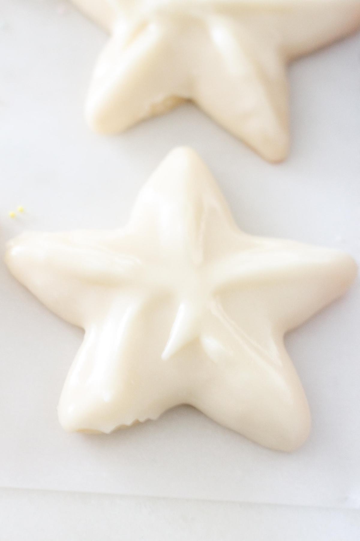 White sugar cookies in star shapes on parchment paper.
