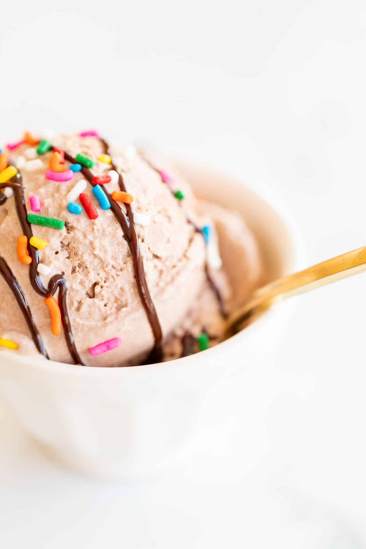white bowl with gold spoon and chocolate ice cream