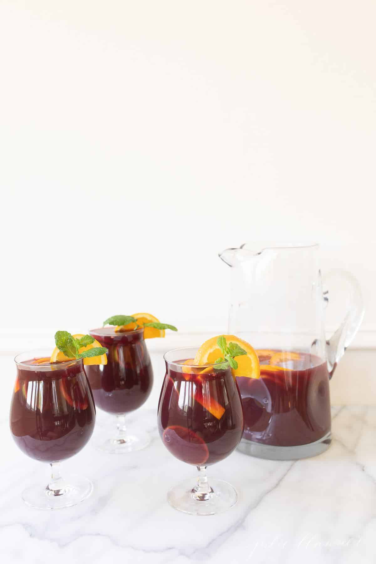 Three glasses of sangria and a pitcher for a Thanksgiving cocktail.