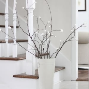 A marshmallow tree made from branches and marshmallows, in a white bucket near a staircase