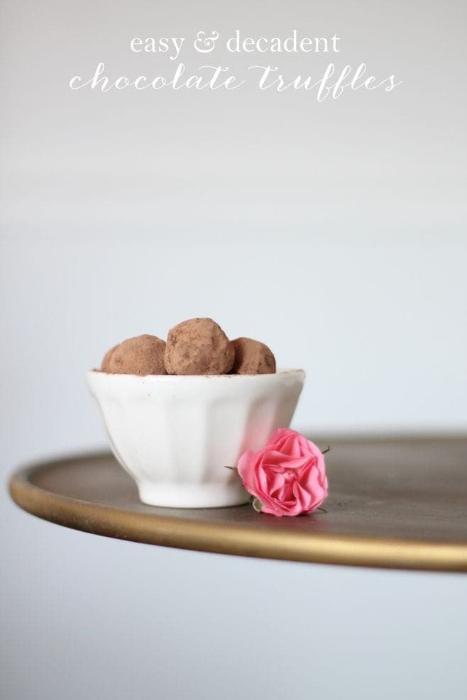 A bowl of chocolate truffles with flowers next to it. 