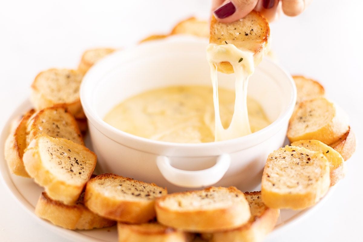 Hot garlic cheese dip stretching out of a white bowl
