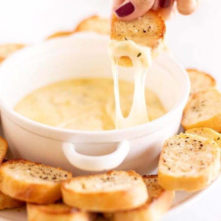 Hot garlic cheese dip stretching out of a white bowl