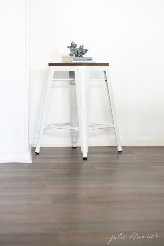 A peel and stick wood floor with a small white stool on top
