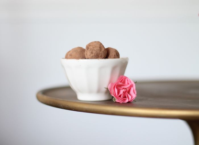 A bowl of chocolate truffles with flowers next to it. 