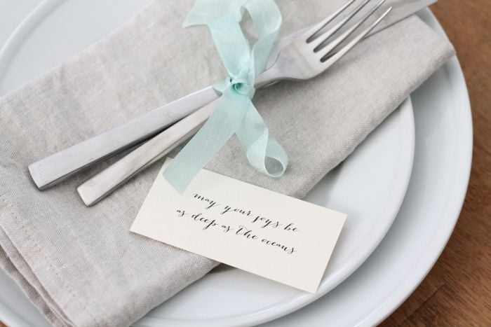 A fork and a knife tied together with ribbon. A small note is to the side.