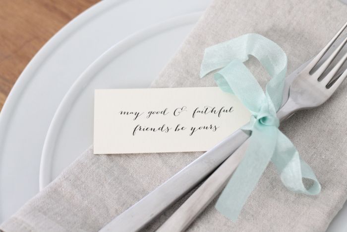 A fork and a knife tied together with ribbon. A small note is to the side.