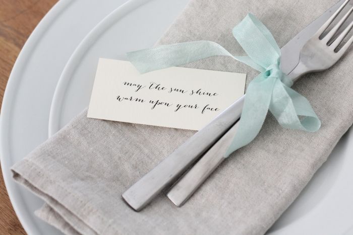 A fork and a knife tied together with ribbon. A small note is to the side.
