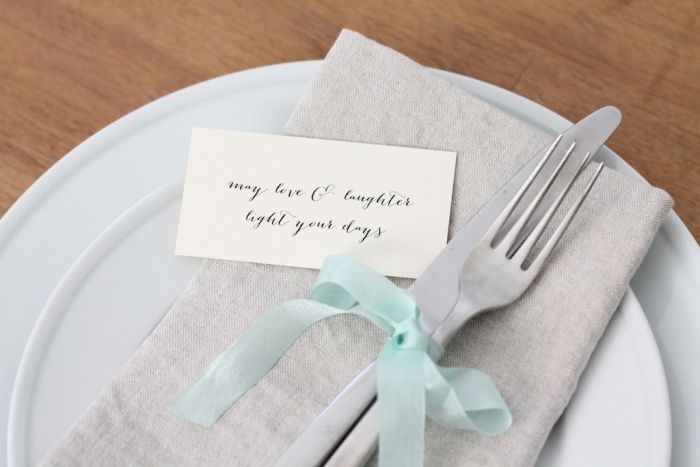 A fork and a knife tied together with ribbon. A small note is to the side.