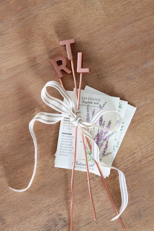 Three copper letter markers tied together with a ribbon and plant seeds as well.