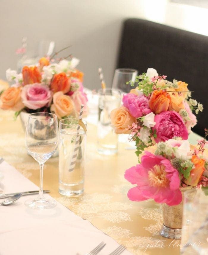 A set table with pink and orange flowers on it.